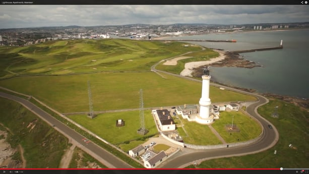 Aerial view of the lighthouse and cottages. Aberdeen city and harbour in the background.