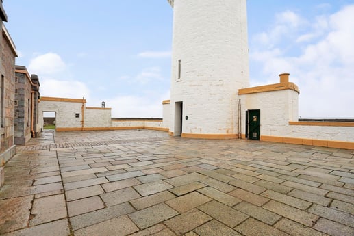 The lighthouse from the court with the cottages on the left.